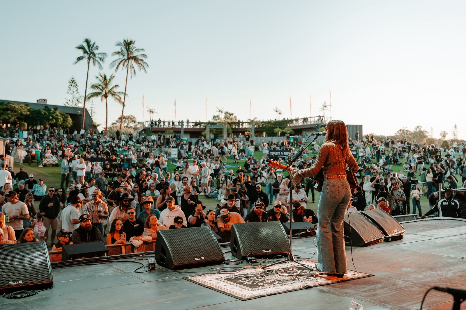 Bianca Joulianou on stage in front of a festival crowd at sunset